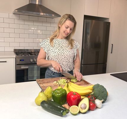 A woman is standing in front of a tray of food in a kitchen.