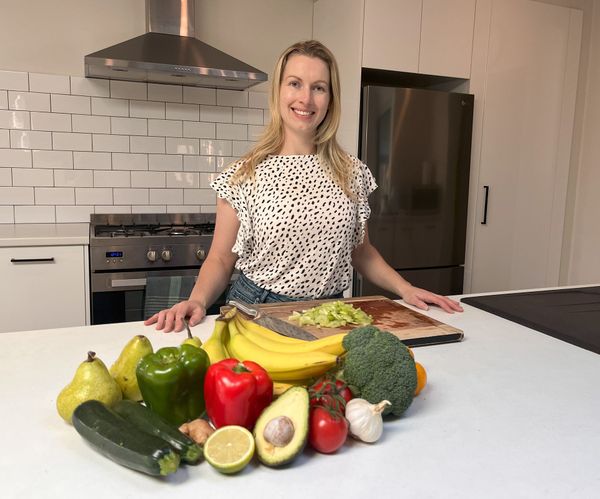 A woman standing next to fruits and vegetables