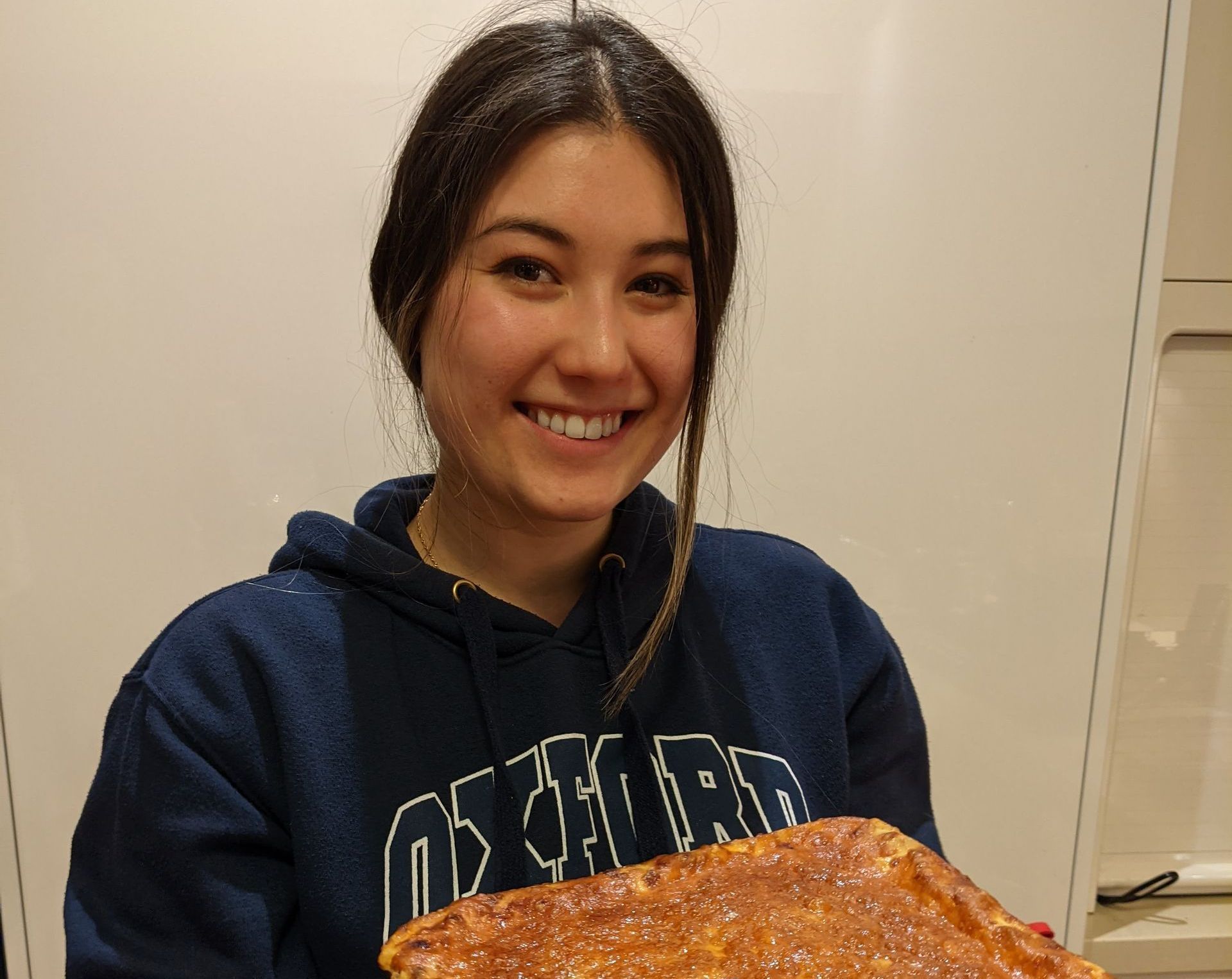 A woman wearing a sweatshirt that says chicago is holding a pizza