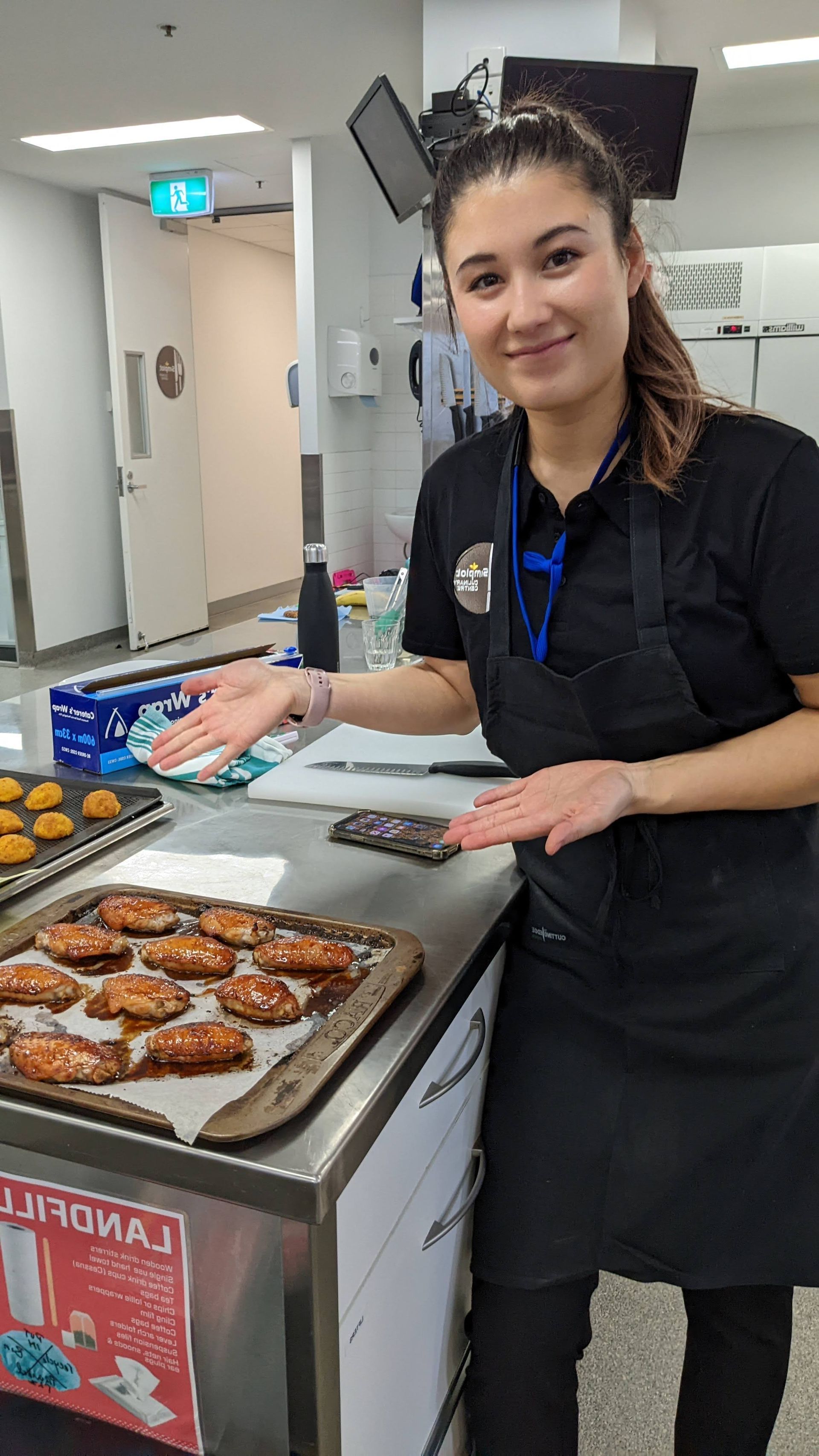 A woman is standing in front of a counter with a tray of cookies on it.