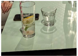 Two glasses of water are on a table next to a cell phone.