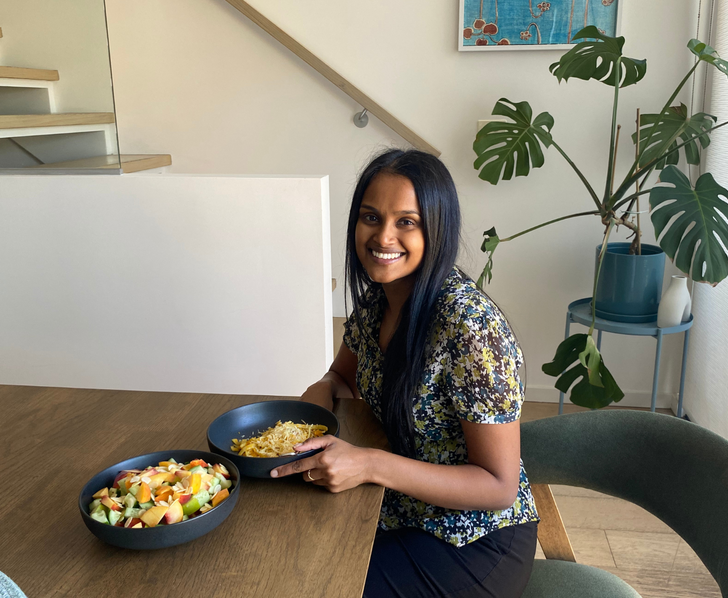A woman is sitting at a table with two bowls of food.