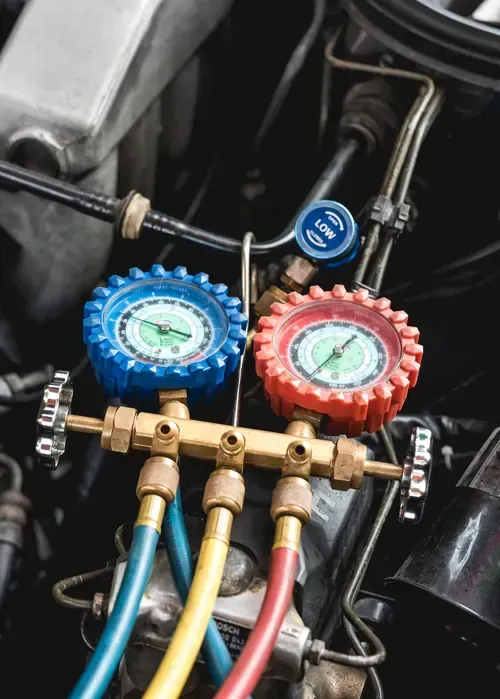 Automotive manifold gauge set connected to an engine bay to measure air conditioning refrigerant pressure.