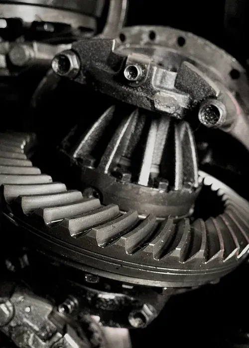 A person holding a red and black digital multimeter to test an engine under the hood of a car.