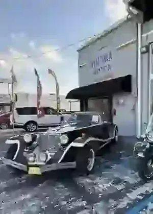 Vintage black Rolls-Royce parked outside Aventra Motor dealership.