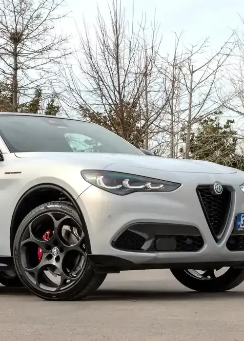 A silver Alfa Romeo Stelvio SUV parked outdoors with prominent dark alloy wheels and red brake calipers.