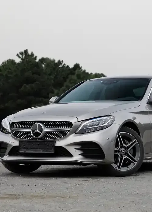 A silver Mercedes-Benz C-Class sedan parked outdoors with trees in the background.