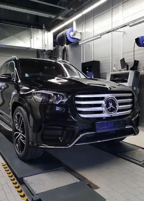 A black Mercedes-Benz SUV parked on a service lift inside an industrial automotive garage.