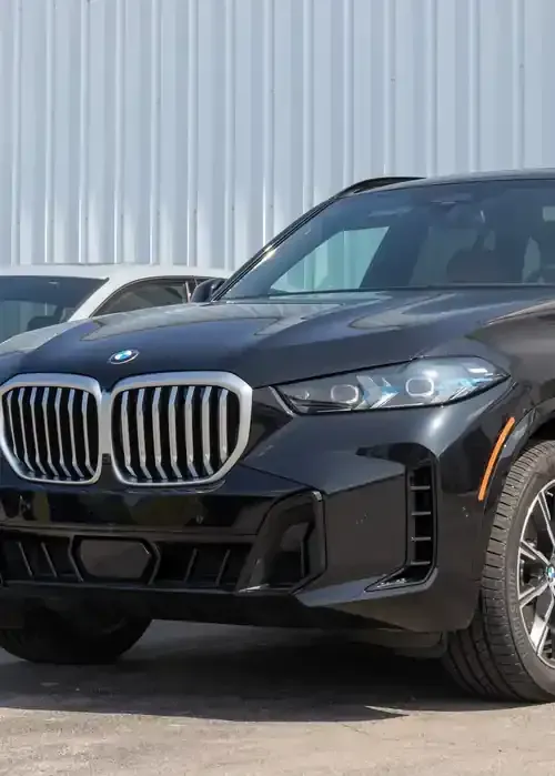 A black BMW X5 SUV parked outside in front of a white corrugated metal wall.