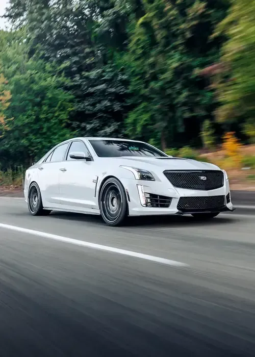 A silver Toyota Tacoma truck driving on a paved road with a large, misty mountain in the background.