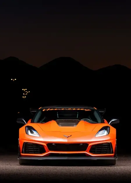 A silver Toyota Tacoma truck driving on a paved road with a large, misty mountain in the background.