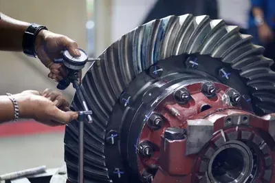 A mechanic's hands work on an alternator installed inside a vehicle's engine bay.