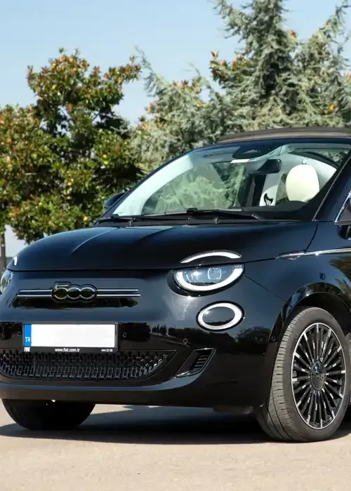 A black Fiat 500 electric convertible parked outdoors with trees in the background.