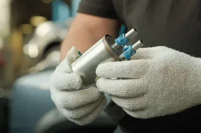 A mechanic's hands work on an alternator installed inside a vehicle's engine bay.