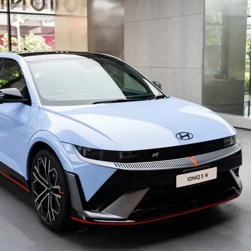 A light blue Hyundai IONIQ 5 N parked indoors, featuring sharp, angular lines, black accents, and red trim along the base.