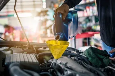 A mechanic's hands work on an alternator installed inside a vehicle's engine bay.