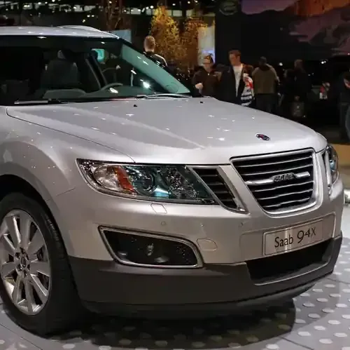 A silver Saab 9-4X SUV parked on a light-colored display floor at an indoor automotive event.