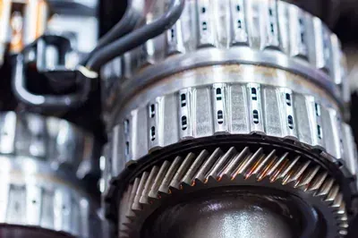 A mechanic's hands work on an alternator installed inside a vehicle's engine bay.