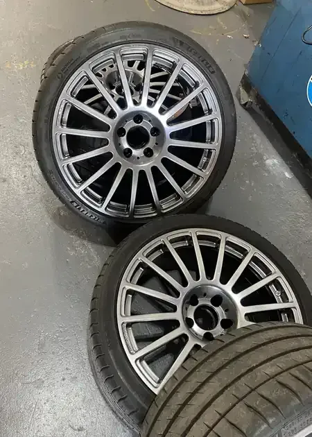 A mechanic's hands work on an alternator installed inside a vehicle's engine bay.