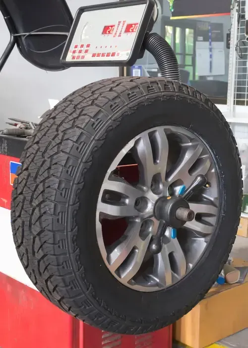 A tire mounted on a wheel balancing machine in a repair shop.