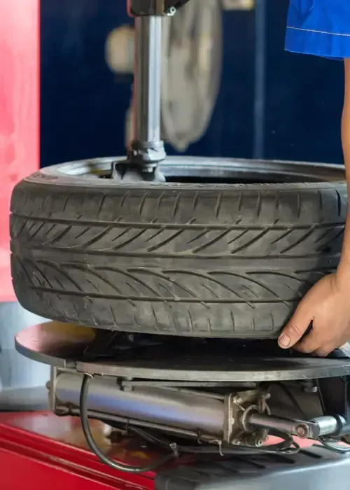 A mechanic uses a tire mounting machine to work on a car tire in a shop.