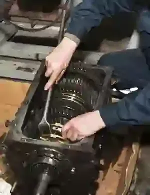 Technician inspecting an open industrial gearbox with exposed gears and shafts on a workbench