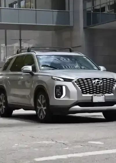 Silver SUV parked on a city street in front of a modern building.