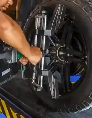 Mechanic installing a wheel alignment clamp on a black car tire in a garage