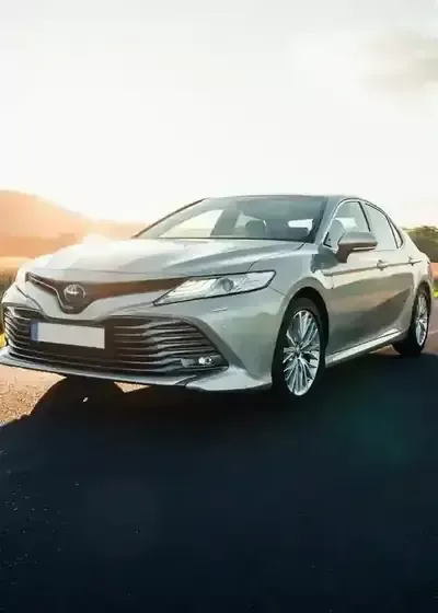 Silver sedan parked on a road at sunset, front three-quarter view