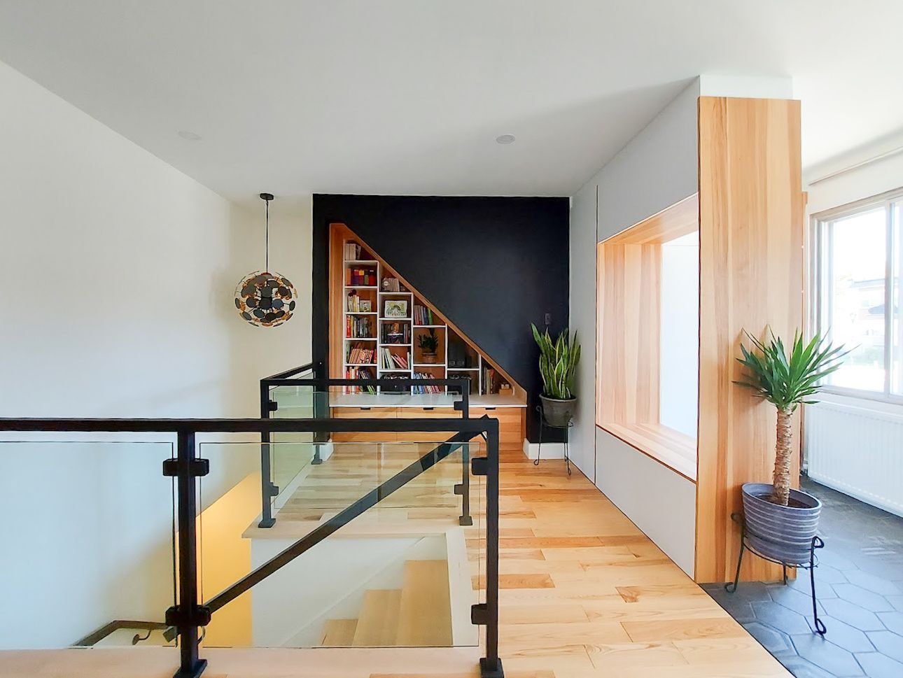 Un escalier avec une rampe en verre et une étagère en dessous.