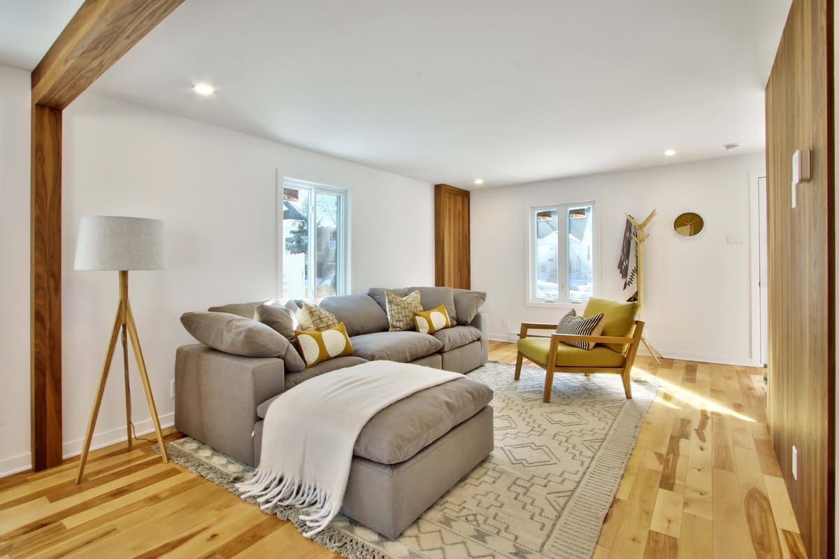 Un salon avec un canapé, une chaise, une lampe et un tapis.