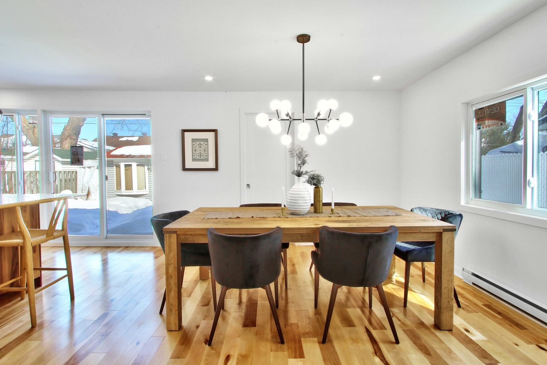 Une salle à manger avec une table et des chaises en bois et un lustre.