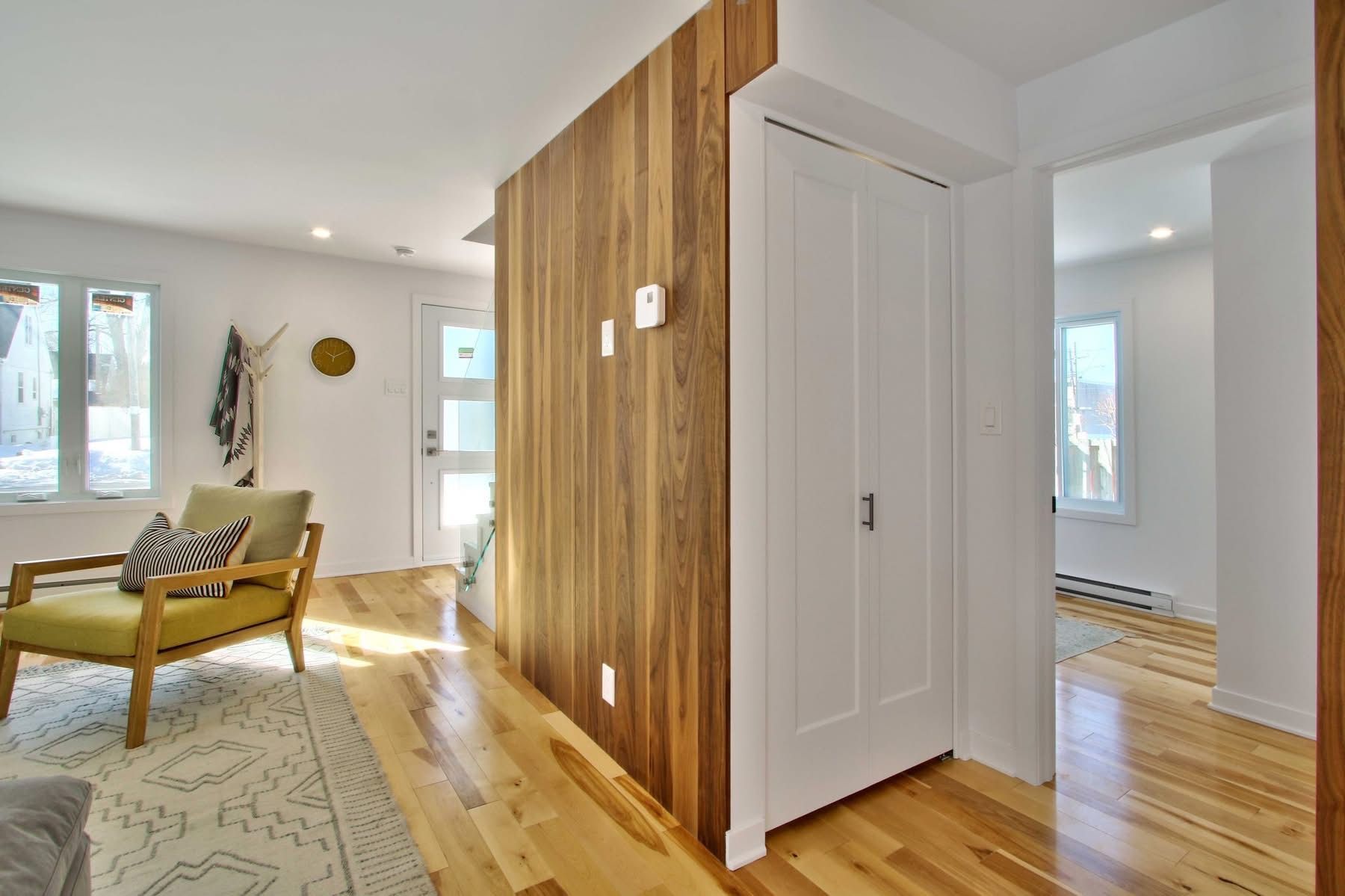 Un salon avec du parquet, une chaise jaune et un mur en bois.
