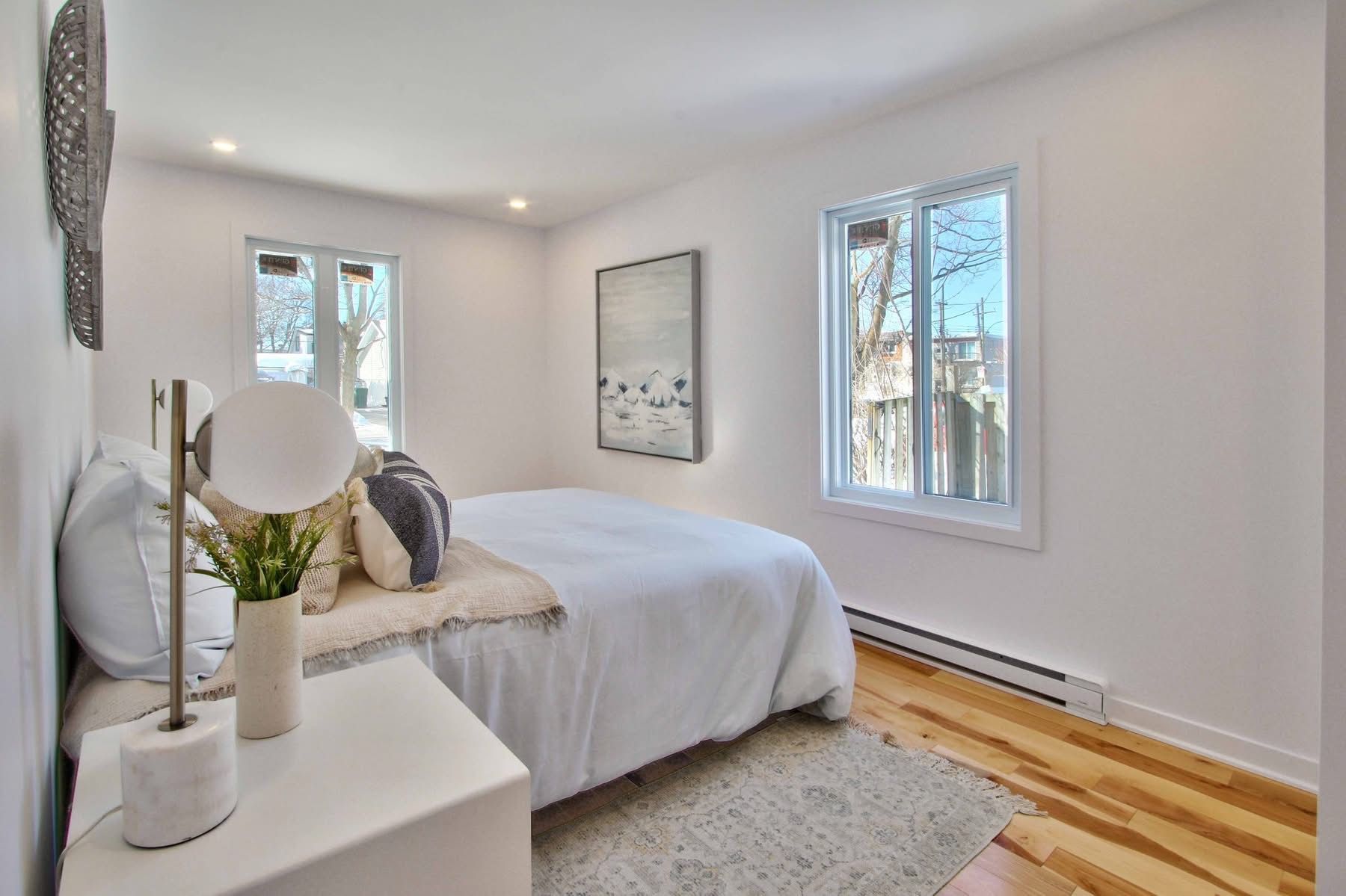 Une chambre avec un lit, une table de chevet, une lampe et une fenêtre.