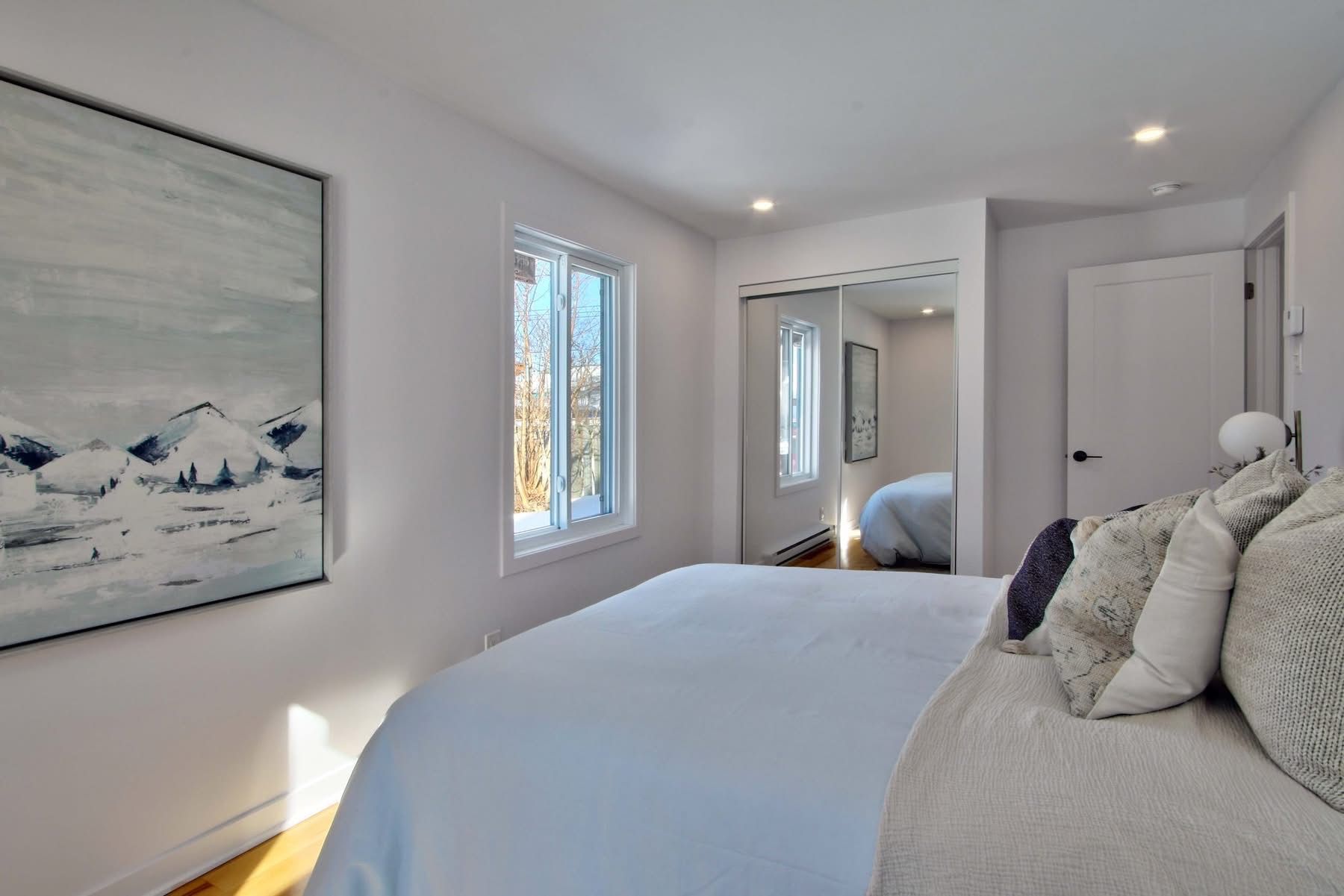 Une chambre avec un grand lit et un tableau au mur.