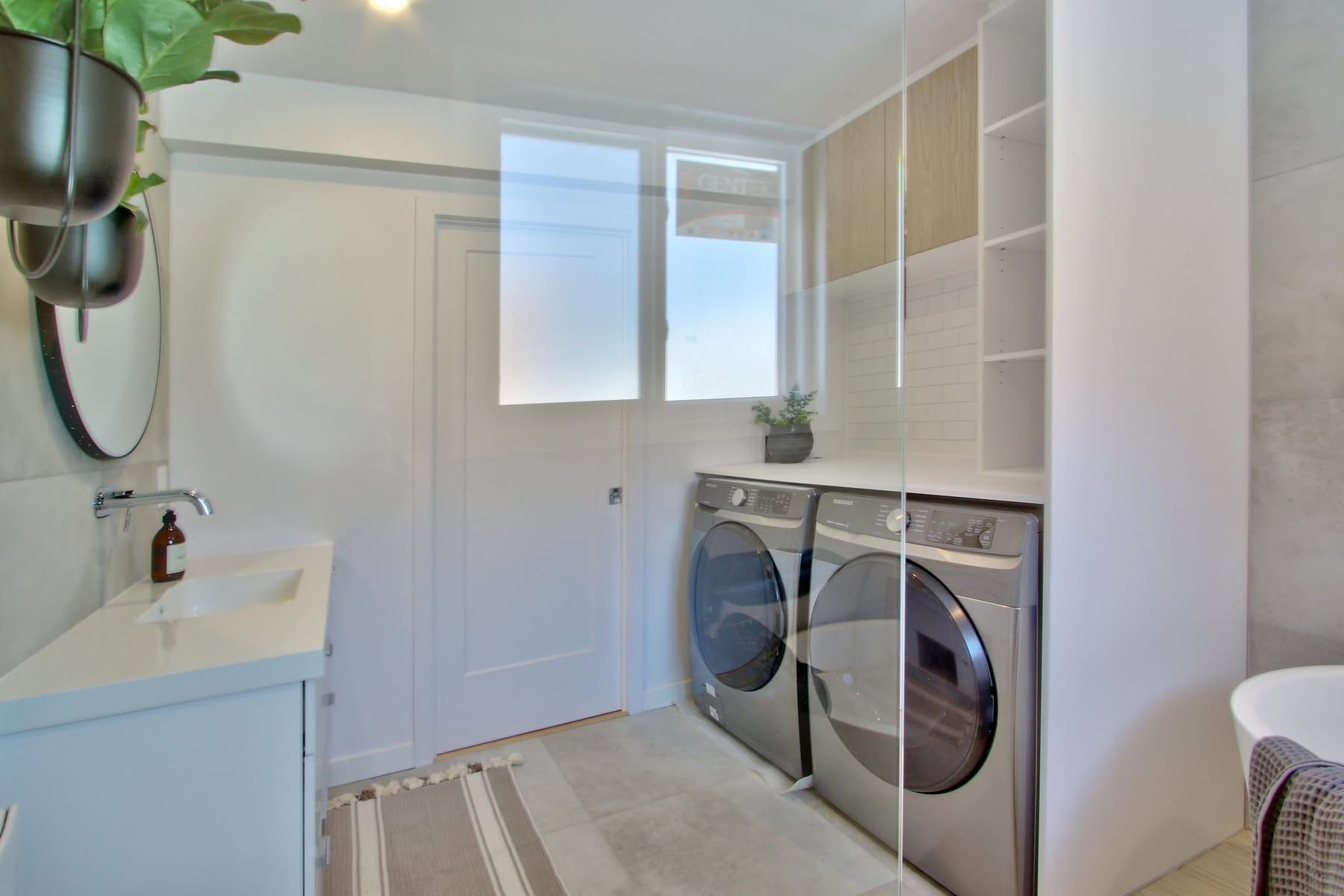 Une buanderie avec laveuse et sécheuse et un évier.