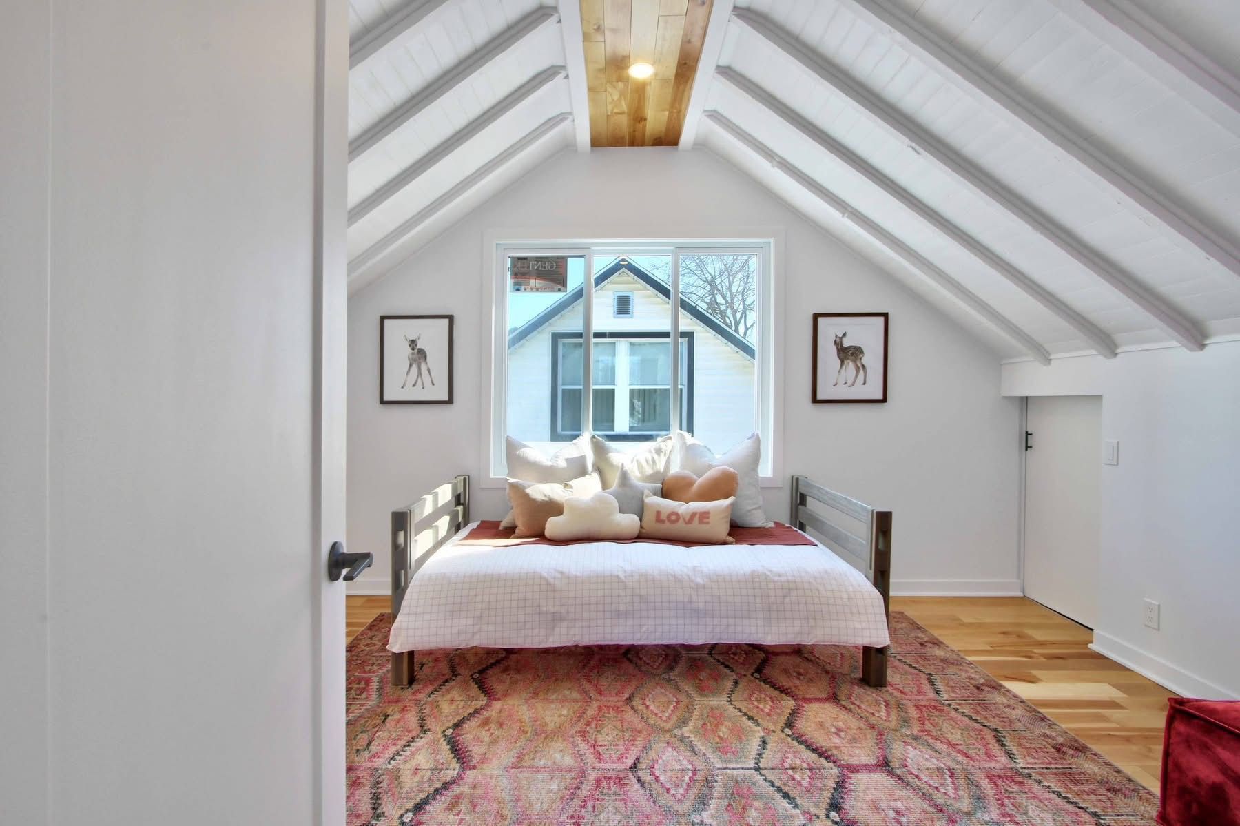 Une chambre avec un lit et un tapis dans le grenier.