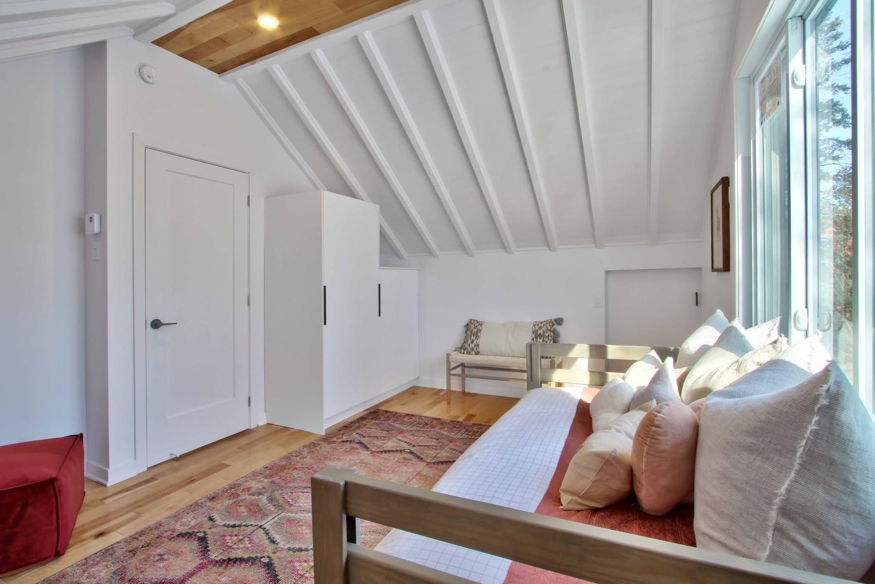 Un salon avec un canapé, une chaise, un tapis et de grandes fenêtres.