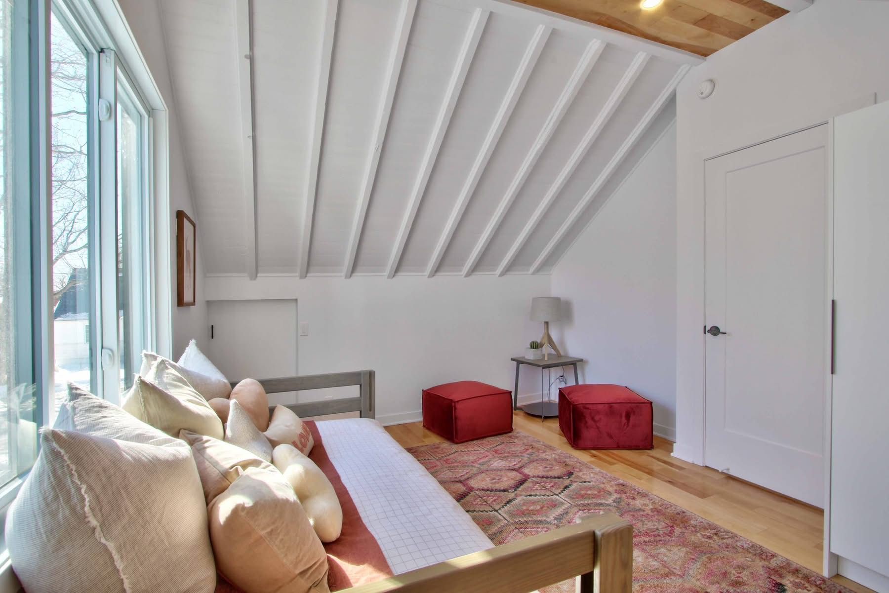 Un salon avec un canapé, des poufs et un tapis.