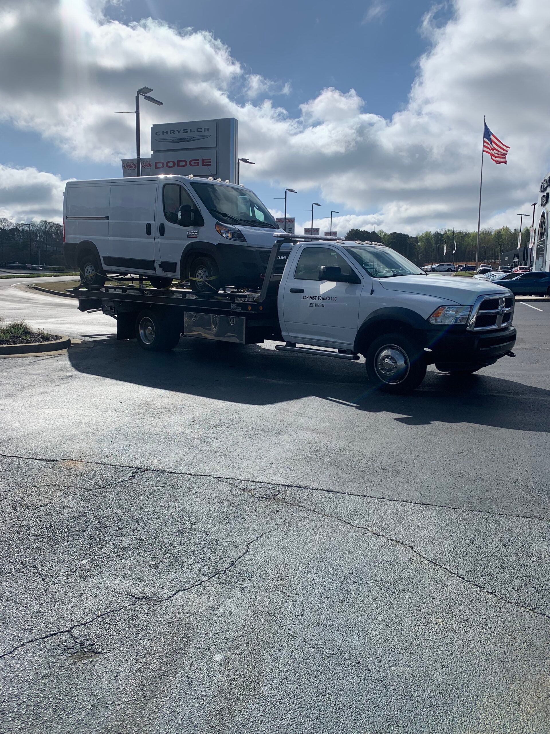 A tow truck is carrying a van and a car.