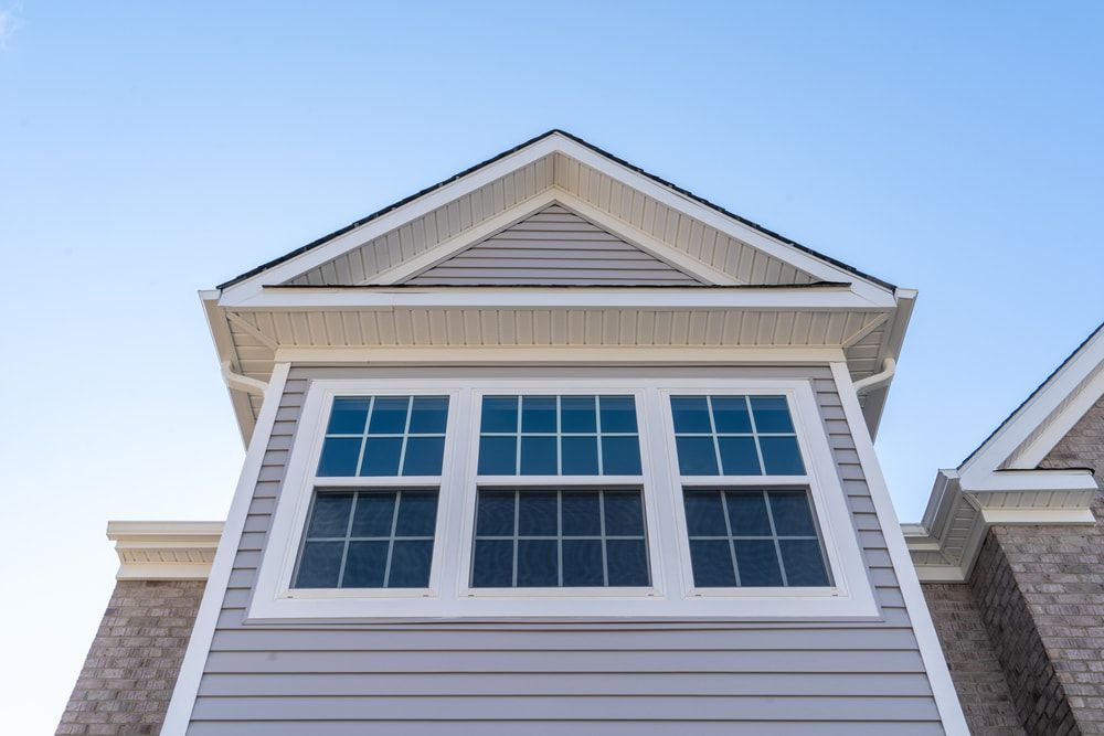 A Low-angle View of a Grey-sided House Gable With a Three-panelled Window — ACG Windows & Glass in Cheltenham, VIC