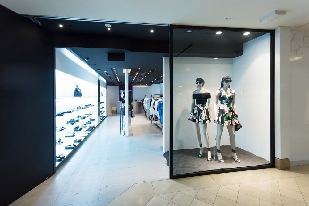 Modern clothing store entrance with mannequins in a glass display case and illuminated shelves inside — ACG Windows & Glass in Lyndhurst, VIC