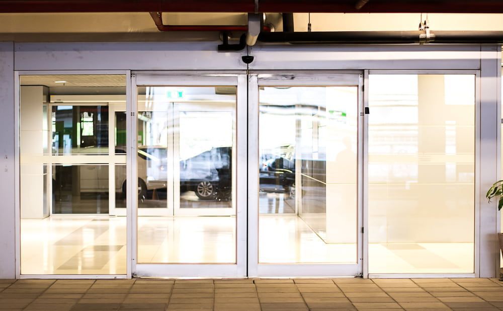 Sliding glass storefront doors with a tiled entrance at night — ACG Windows & Glass in Lyndhurst, VIC
