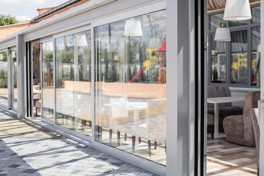 Modern glass-walled patio with sliding doors, outdoor seating, and bright sunlight — ACG Windows & Glass in Mount Eliza, VIC