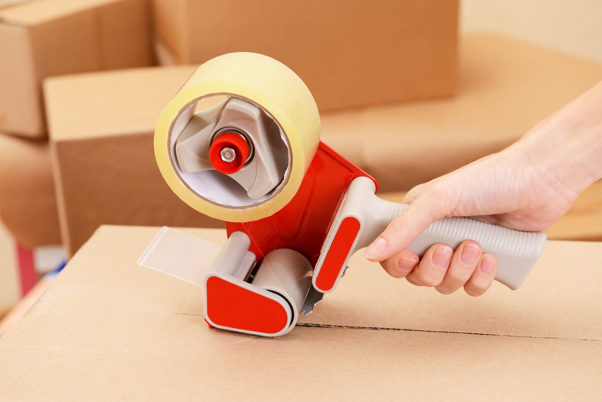 Hand Sealing a Cardboard Box With a Tape Gun — The Move It Man In Tablelands, QLD
