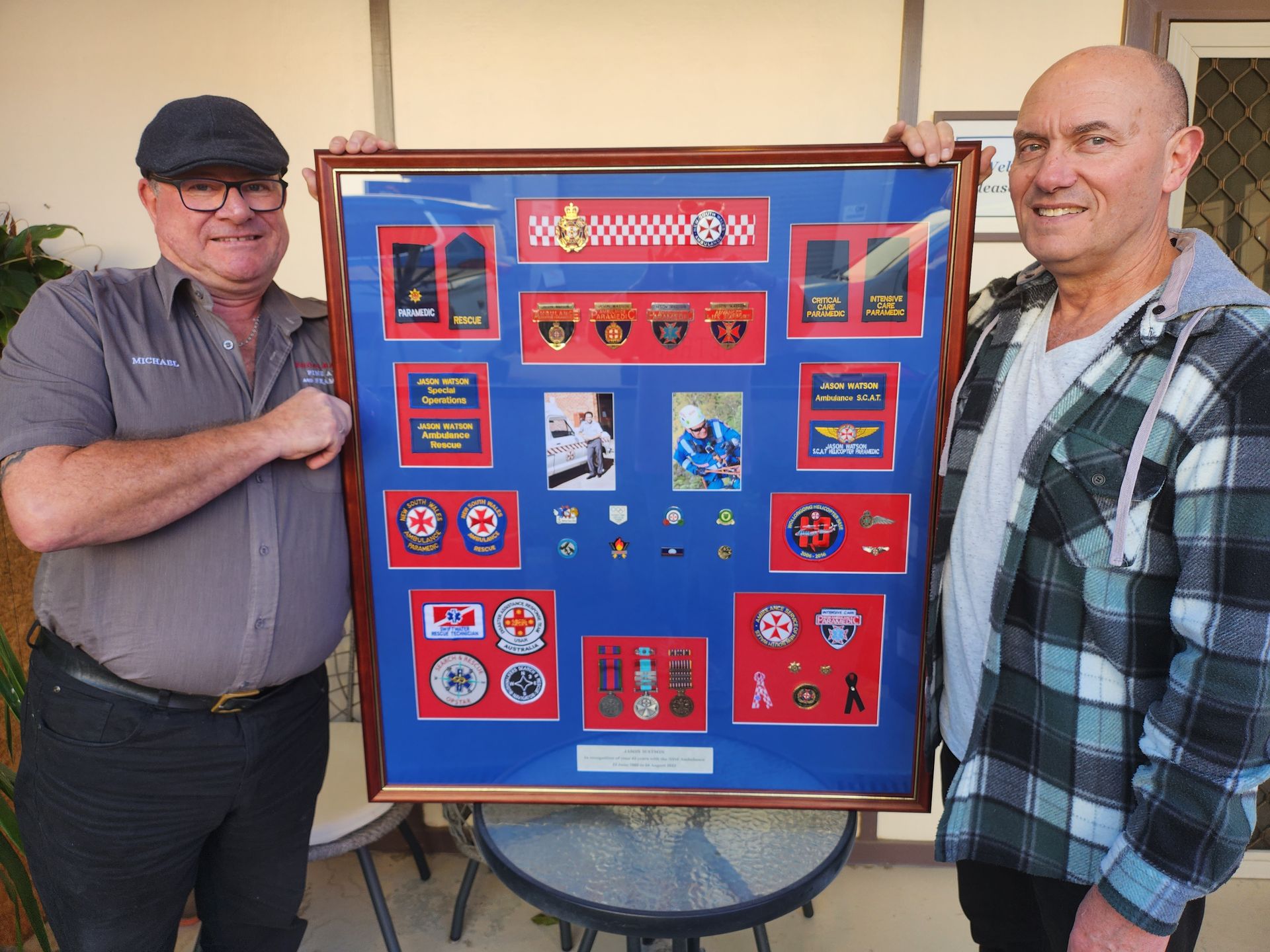 Two men are standing next to each other holding a framed picture.
