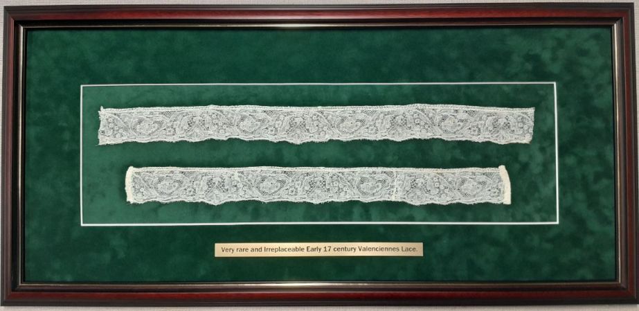 Two pieces of lace are displayed in a wooden frame.