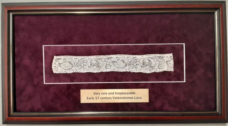 A framed piece of lace with a purple background