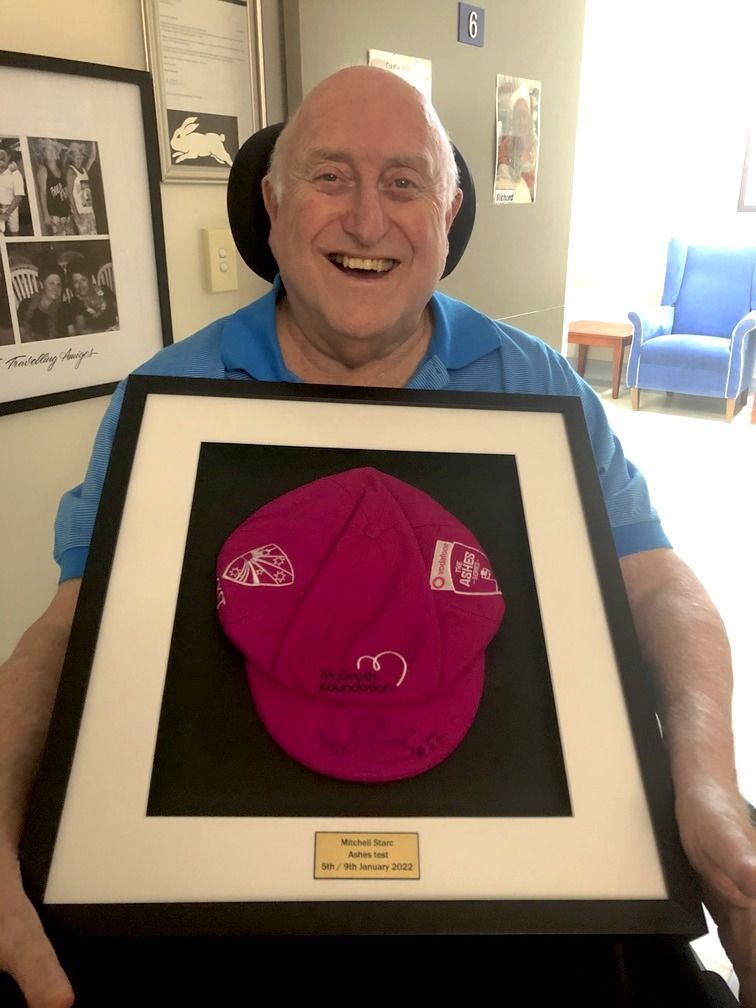 A man in a blue shirt is holding a framed hat