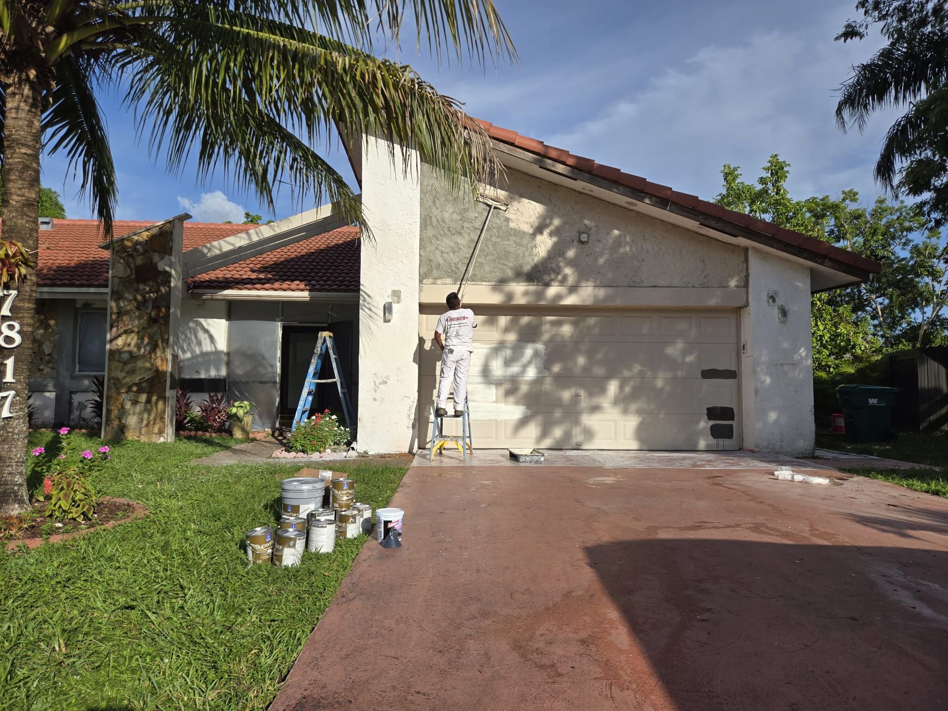 A man is standing on a ladder painting a house